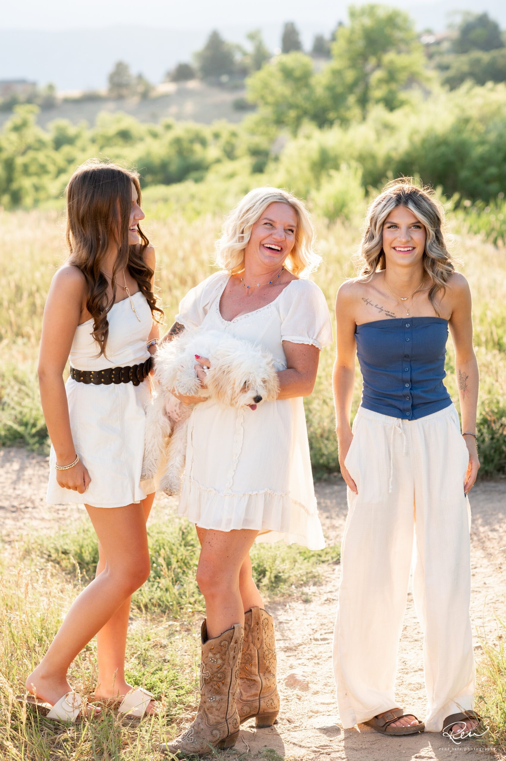 a family of five stand together in an open field of golden grass with their family dog and mountains in the background in Colorado Springs CO
